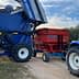 New Holland olive harvester unloading olives into a red trailer attached to a blue tractor. - Olive Oil Times
