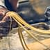 A hand holding freshly rolled pasta strands from a pasta machine in a kitchen setting. - Olive Oil Times