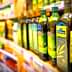 Various bottles of olive oil displayed on a store shelf in a grocery aisle. - Olive Oil Times