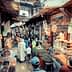A bustling market scene in a traditional bazaar with various stalls and shoppers. - Olive Oil Times