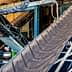 Industrial conveyor belt system with multiple inclined belts and metal framework. - Olive Oil Times