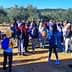A large group of students gathered in an olive grove, wearing backpacks and casual clothing. - Olive Oil Times