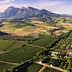 Aerial view of agricultural fields with mountains in the background in a rural landscape. - Olive Oil Times