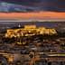 View of the Acropolis of Athens illuminated at sunset with a colorful sky and distant mountains. - Olive Oil Times