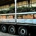 Truck transporting wooden crates filled with olive branches on a flatbed trailer. - Olive Oil Times