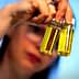 Person holding two small glass bottles containing olive oil with yellow liquid inside. - Olive Oil Times