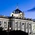 The Royal Palace of Madrid with a domed roof and decorative architecture illuminated at dusk. - Olive Oil Times