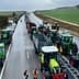 Line of tractors on a highway during a protest with people walking nearby. - Olive Oil Times