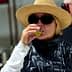 Woman wearing a straw hat and sunglasses tasting olive oil in a factory setting. - Olive Oil Times