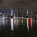 Night view of the New York City skyline with illuminated buildings reflecting on the water. - Olive Oil Times
