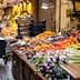 Vibrant display of various fruits and vegetables in a market setting with carts and crates. - Olive Oil Times
