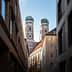 View of the twin towers of Munich's Cathedral framed by surrounding buildings. - Olive Oil Times