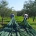 Two individuals walking through an olive grove while carrying green harvesting nets. - Olive Oil Times