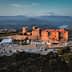Aerial view of a historic castle surrounded by mountains and greenery. - Olive Oil Times