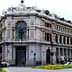 A large historic building in Madrid featuring ornate architectural details and a clock on the facade. - Olive Oil Times