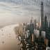Aerial view of Shanghai skyline featuring tall buildings and a river flowing through the city. - Olive Oil Times