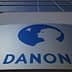 Danone company logo displayed on a building facade with a blue silhouette of a child's profile. - Olive Oil Times