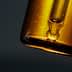 Close-up of an amber glass dropper bottle with a pipette top against a dark background. - Olive Oil Times