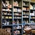 Wooden shelves filled with jars, bottles, and packaged food items in a grocery store. - Olive Oil Times