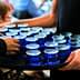 A tray holding multiple blue glasses filled with olive oil being served at an event. - Olive Oil Times