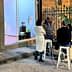 A group of four people gathered around a table outside an art gallery, engaged in conversation. - Olive Oil Times
