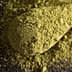 Green powdered substance on a wooden spoon, with loose powder scattered around. - Olive Oil Times