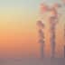 Three smoke stacks emitting vapor into the sky during sunrise with a gradient of colors. - Olive Oil Times