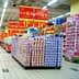 Allée de supermarché avec des présentoirs de produits empilés et des panneaux promotionnels en chinois. - Olive Oil Times