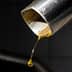 近距離觀察橄欖油從金屬噴嘴滴入容器中。 - Olive Oil Times