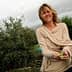 Žena duge kose u bež džemperu s maslinama u rukama na otvorenom. - Olive Oil Times