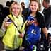 Deux femmes tenant des verres lors d'un événement social, l'une portant un gilet jaune et l'autre une robe fleurie. - Olive Oil Times