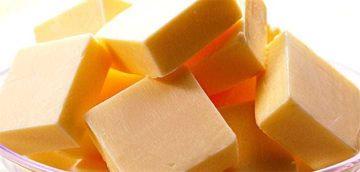 Several yellow butter cubes stacked together in a clear bowl. - Olive Oil Times