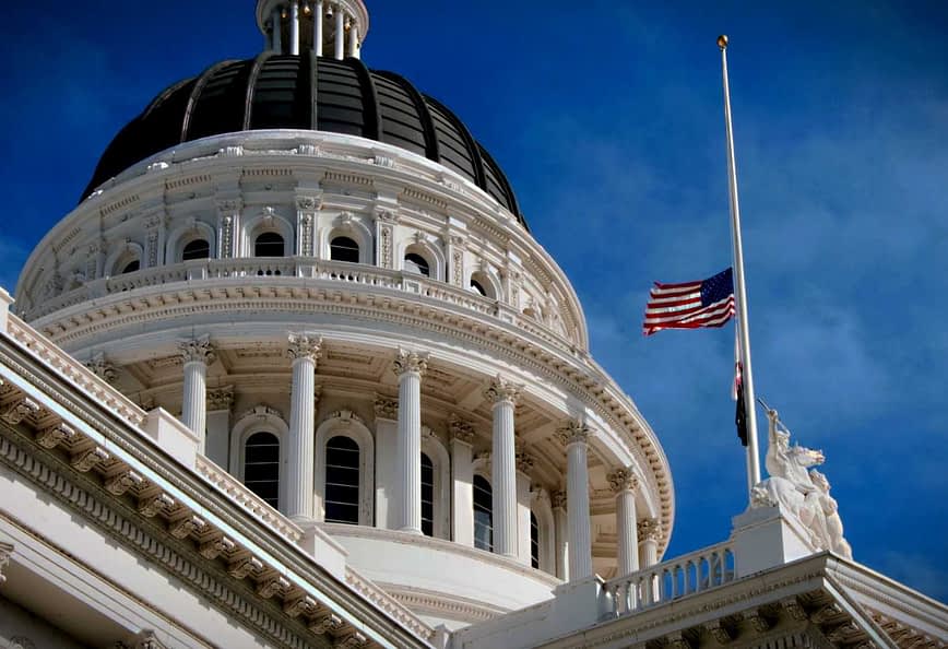 Close-up view of the California State Capitol building with a flag at half-mast. - Olive Oil Times
