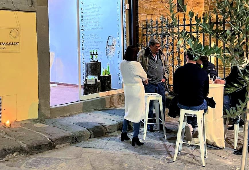 A group of four people gathered around a table outside an art gallery, engaged in conversation. - Olive Oil Times