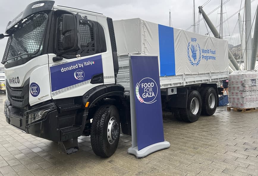 Iveco truck with World Food Programme branding, parked next to a sign for Food for Gaza initiative. - Olive Oil Times