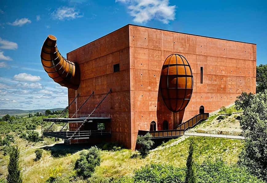 A large, red architectural building with a prominent spherical and cylindrical design element. - Olive Oil Times