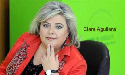 Portrait of Clara Aguilera with a green background, wearing a red jacket and a watch. - Olive Oil Times