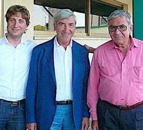 Three men standing together, one in a blue blazer, one in a white shirt, and one in a pink shirt. - Olive Oil Times
