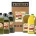 Various bottles of olive oil in different sizes alongside a cardboard box labeled with product information. - Olive Oil Times