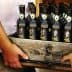 A wooden crate filled with bottles of Willow Creek olive oil held by two people. - Olive Oil Times