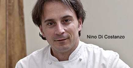 Portrait of chef Nino Di Costanzo wearing a white chef's coat and looking directly at the camera. - Olive Oil Times