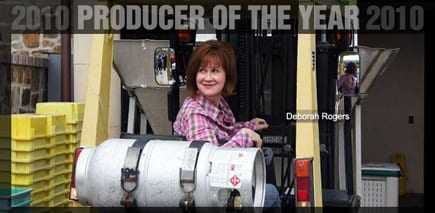 Deborah Rogers sitting on a forklift, labeled '2010 Producer of the Year'. - Olive Oil Times