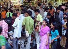 A busy market scene with a diverse group of people shopping and browsing various items. - Olive Oil Times