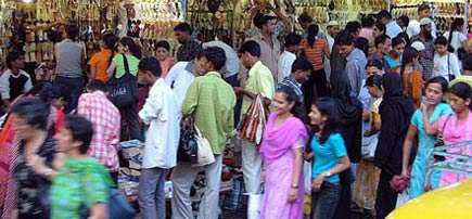 A busy market scene with a diverse group of people shopping and browsing various items. - Olive Oil Times
