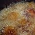 Bubbling oil in a pot during the deep frying process with food submerged. - Olive Oil Times