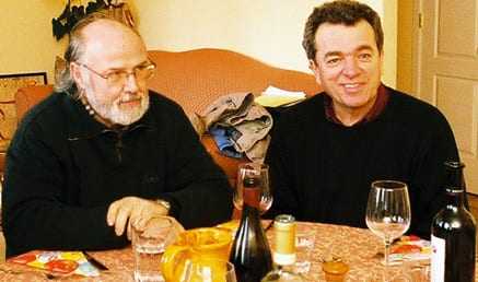 Two men seated at a table with glasses of wine and a bottle in front of them. - Olive Oil Times