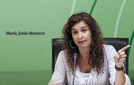 Maria Jesus Montero gesturing while speaking at a conference with a green background. - Olive Oil Times