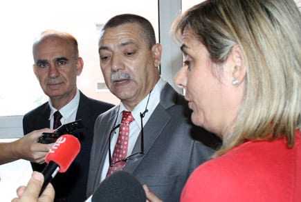 Three individuals, two men and one woman, engaged in a discussion with microphones present. - Olive Oil Times