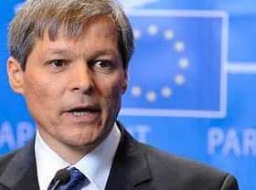 Dacian Ciolos speaking during a press conference in front of a blue backdrop with the European Union flag. - Olive Oil Times