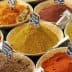 Bowls filled with various spices, each labeled with a small black sign for identification. - Olive Oil Times